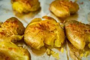 Several smashed potatoes with spices on a tray