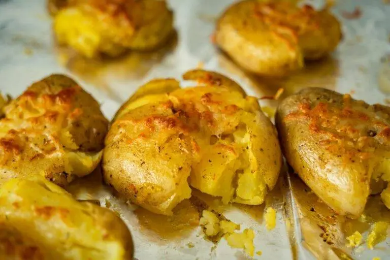 Several smashed potatoes with spices on a tray