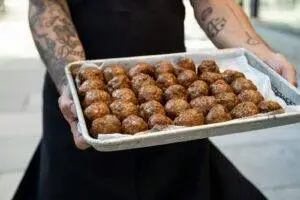 a person holding a tray of doughnuts on a sidewalk