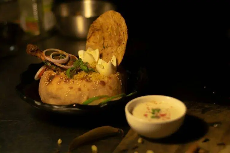 a black plate topped with food and a bowl of sauce