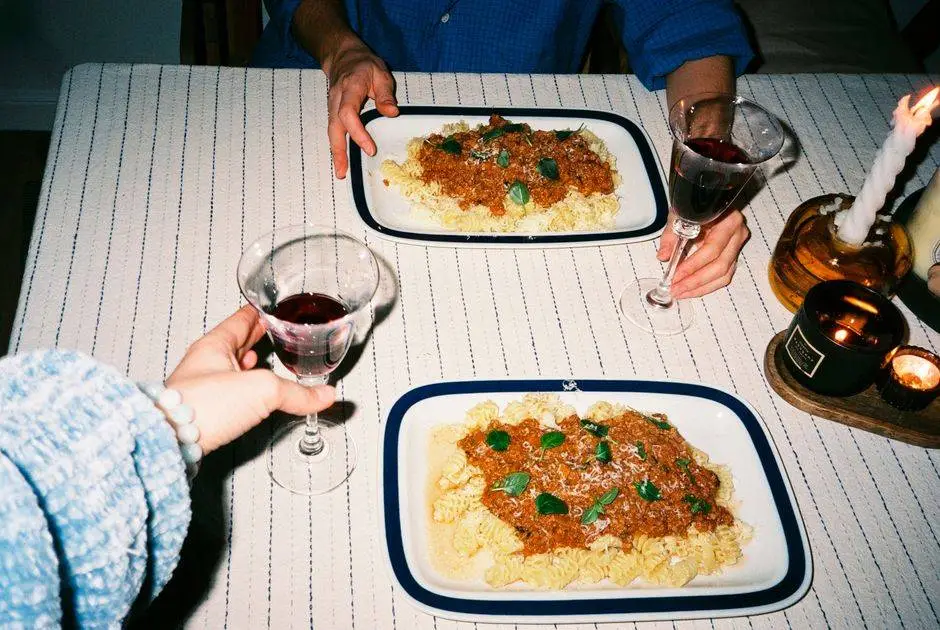 A cozy dinner setting with pasta, wine, and candlelight. Perfect for romantic or casual dining scenes.