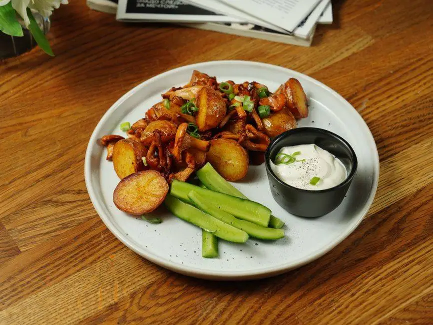 A delectable plate of roast potatoes served with chanterelle mushrooms and fresh cucumbers.