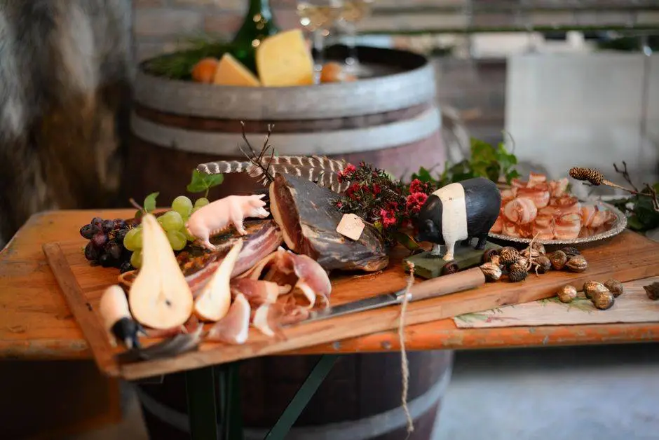 High angle of various delicious meat snacks consisting of jamon and bacon served with pig figures and grapes