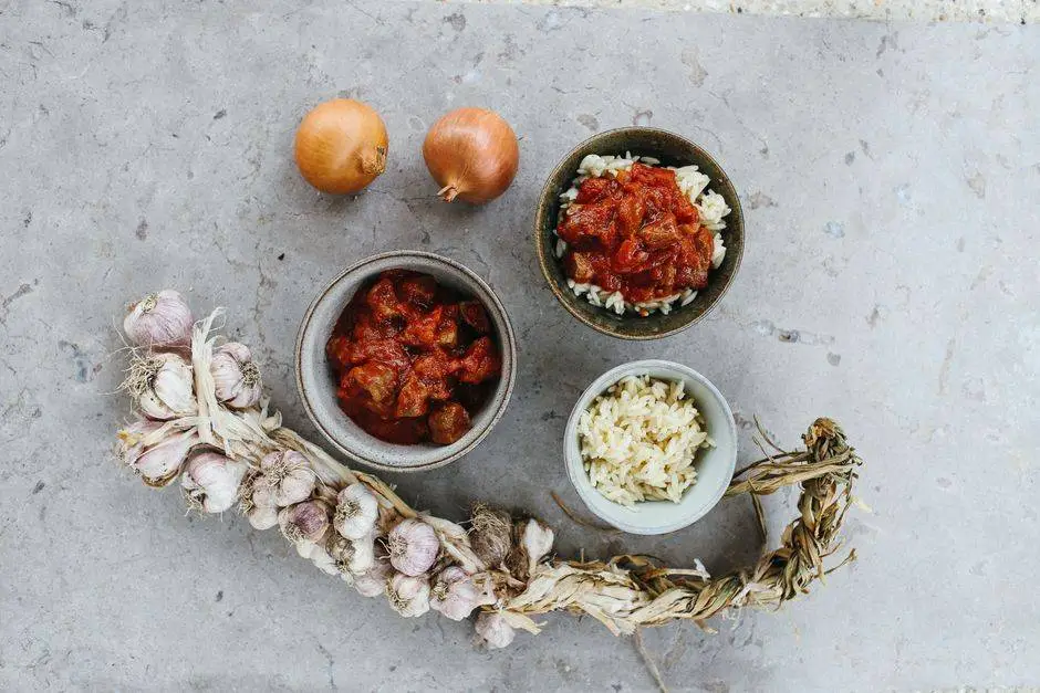 A savory chicken curry plated with rice, garnished with garlic and onions on a textured surface.